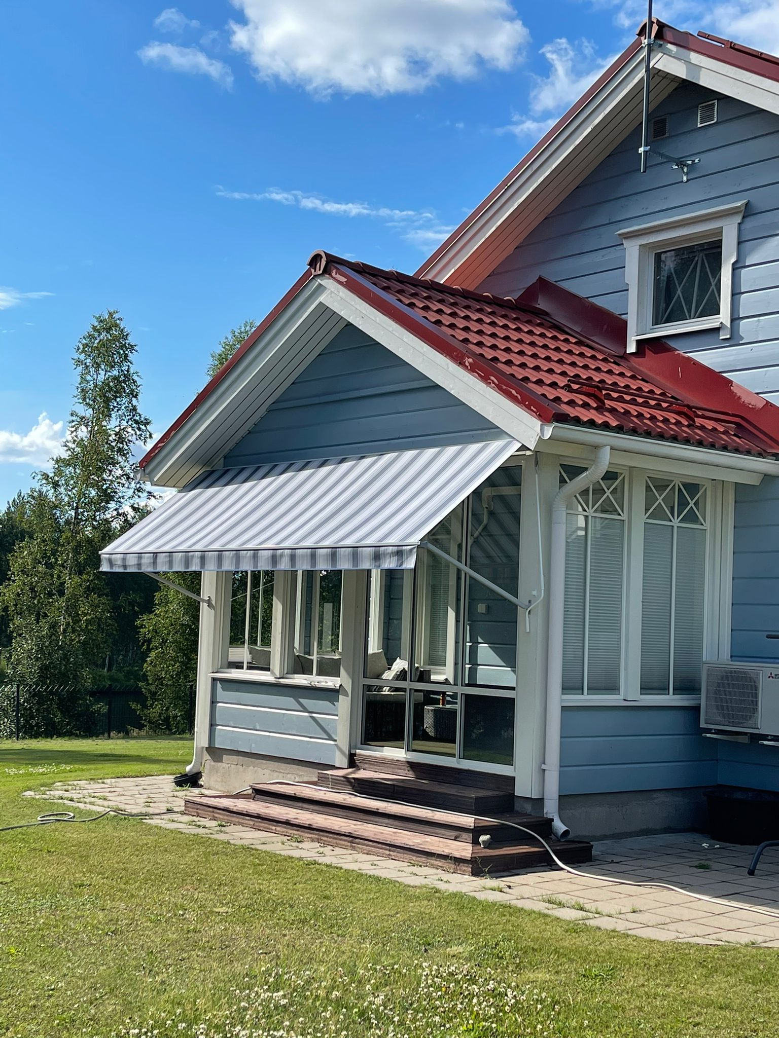 Vaaleanharmaa ikkunamarkiisi punakattoisen omakotitalon päädyssä