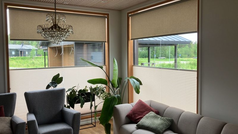 Olohuoneen ikkunoissa rullaverhot ylhäällä ja vaaleat vekkiverhot alhaalla