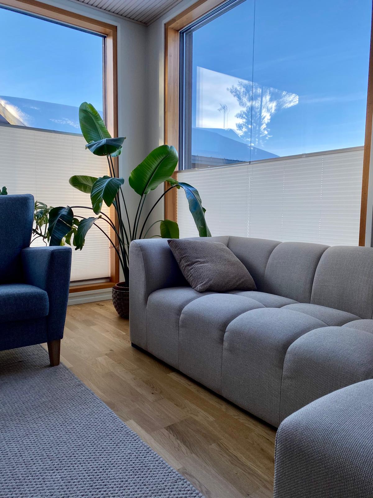 Valkoiset vekkiverhot olohuoneen suurten ikkunoiden alaosassa